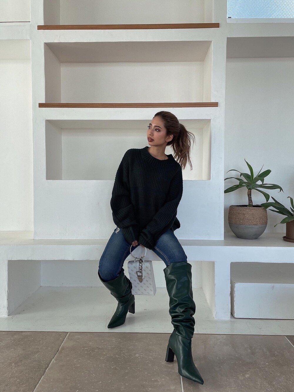 グリーン系のニット/セーター、グリーン系のブーツ、ブルー系のデニムパンツを着用したレディースの冬コーディネートの2枚目の写真