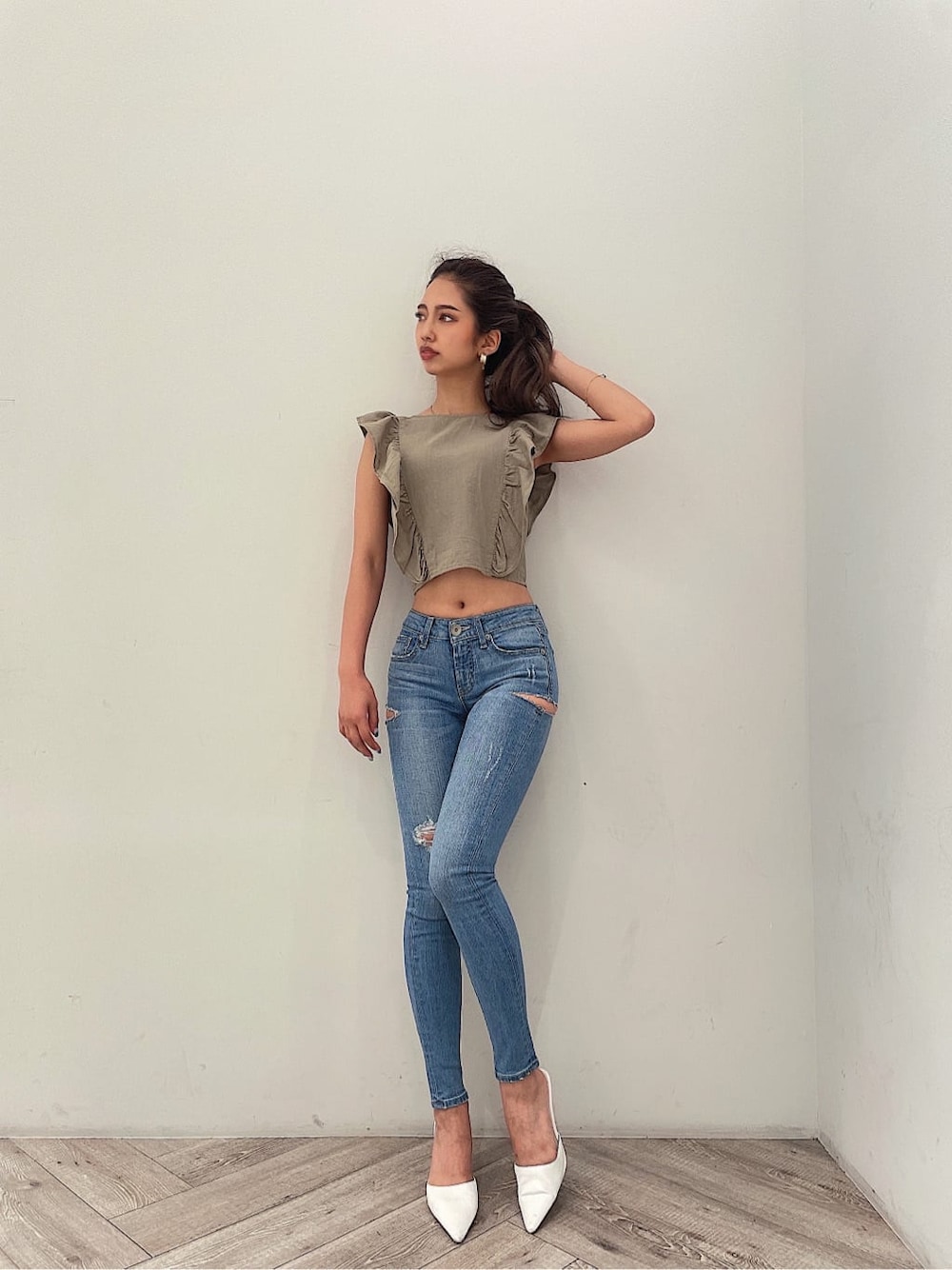 ホワイト系のパンプス、ブルー系のデニムパンツ、ゴールド系のピアス（両耳用）を着用したレディースの夏コーディネートの5枚目の写真