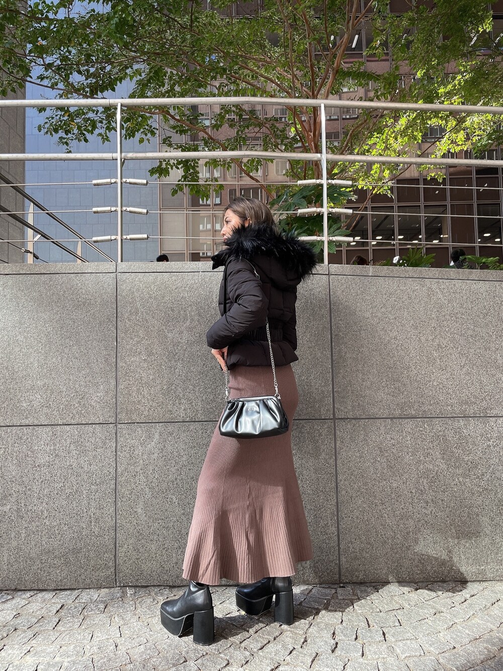 ブラック系のクラッチバッグ、ブラック系のブーツ、ブラウン系のワンピースを着用したレディースの秋コーディネートの5枚目の写真