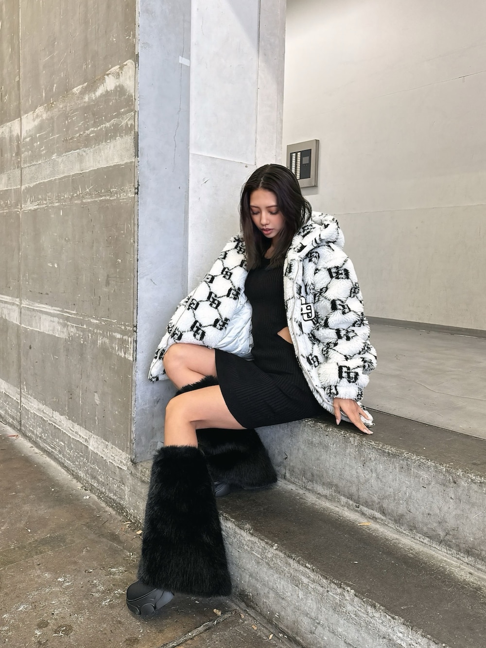 ホワイト系のブルゾン、ブラック系のワンピース、ブラック系のブーツを着用したレディースの秋コーディネートの2枚目の写真