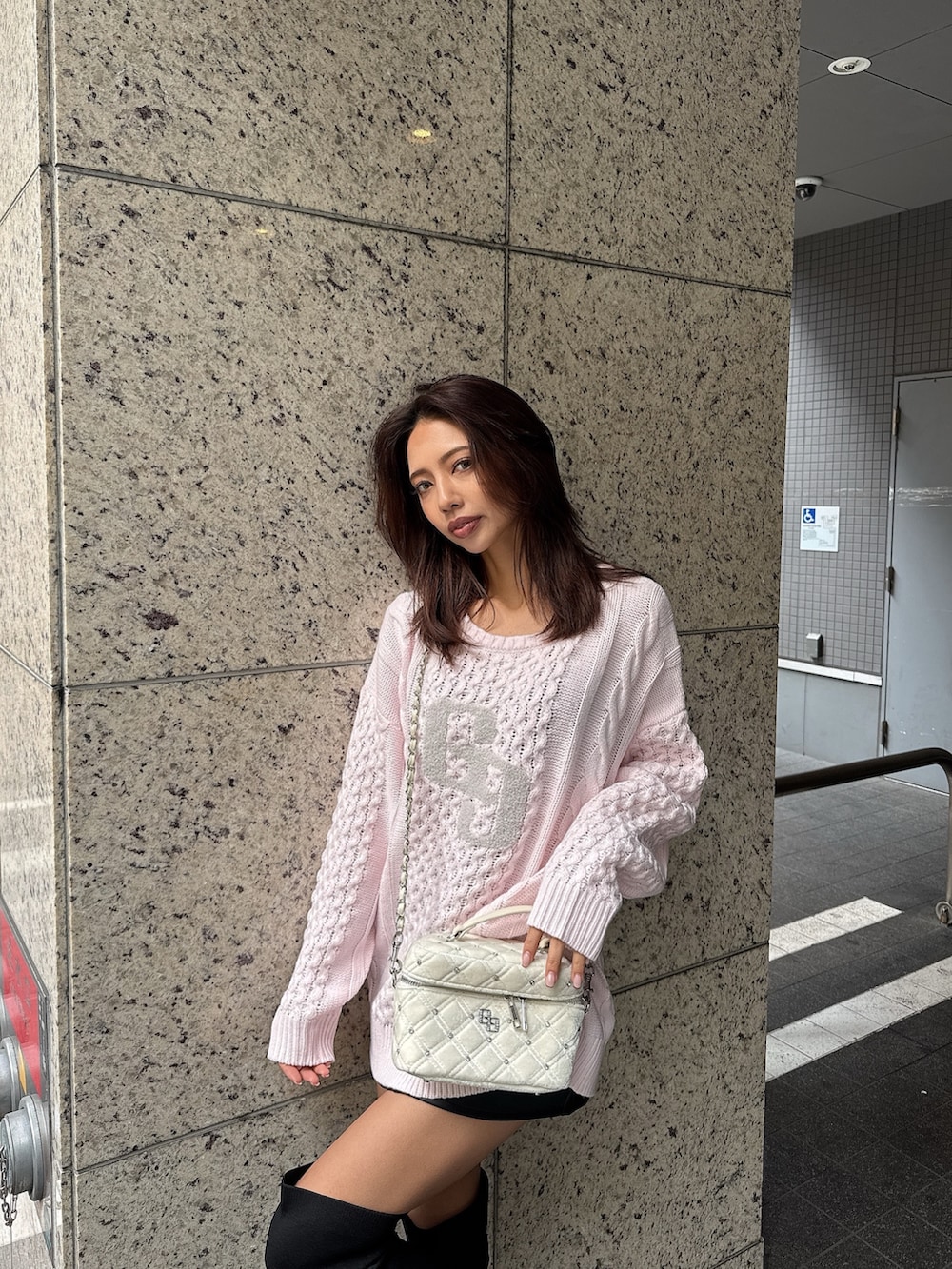 ピンク系のニット/セーター、ブラック系のブーツ、ブラック系のスカートを着用したレディースの秋コーディネートの5枚目の写真