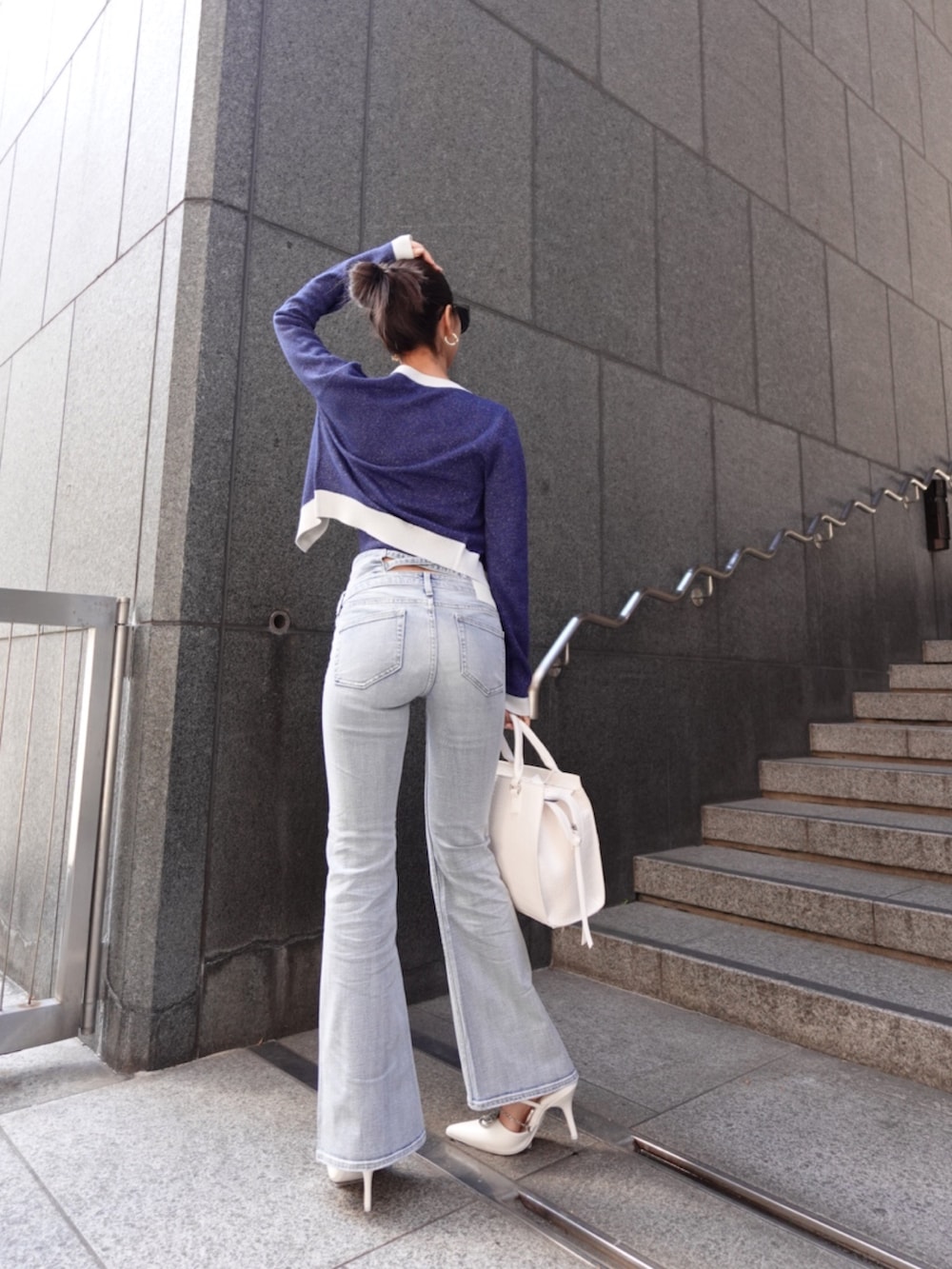 ブルー系のニット/セーター、ブルー系のデニムパンツ、ホワイト系のパンプスを着用したレディースの春コーディネートの6枚目の写真