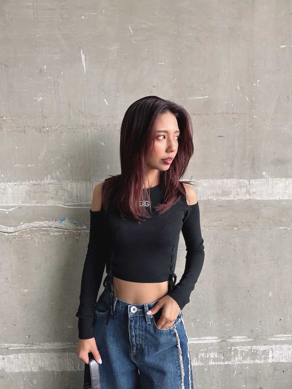 ブルー系のデニムパンツ、ブラック系のニット/セーター、ブラック系のハンドバッグを着用したレディースの秋コーディネートの6枚目の写真