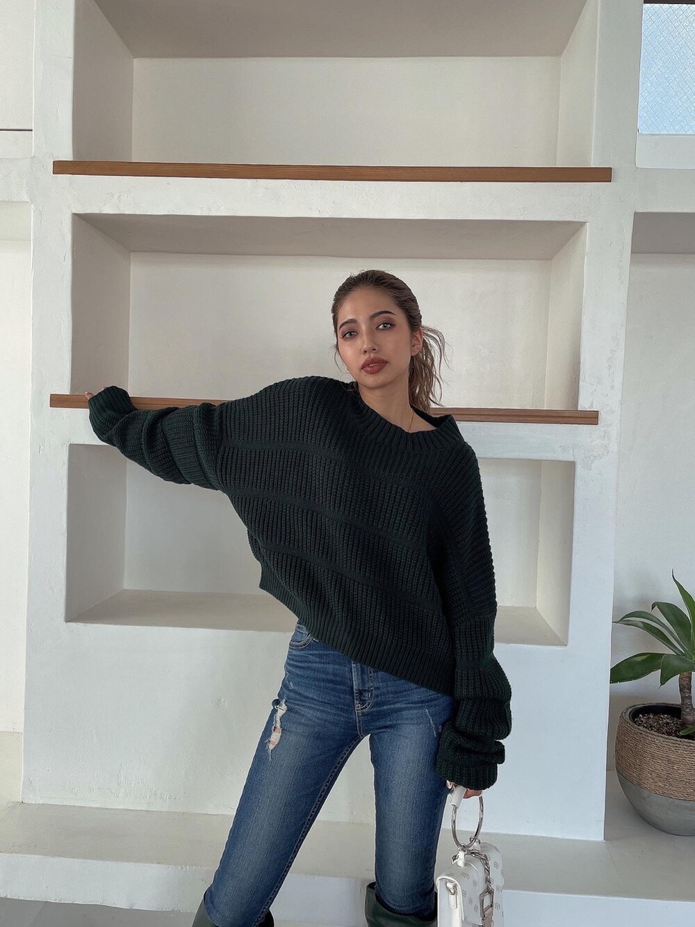 グリーン系のニット/セーター、グリーン系のブーツ、ブルー系のデニムパンツを着用したレディースの冬コーディネートの5枚目の写真