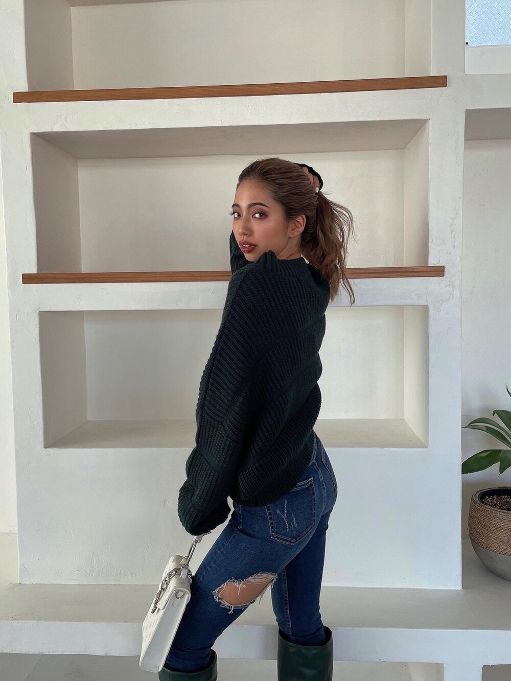 グリーン系のニット/セーター、グリーン系のブーツ、ブルー系のデニムパンツを着用したレディースの冬コーディネートの4枚目の写真