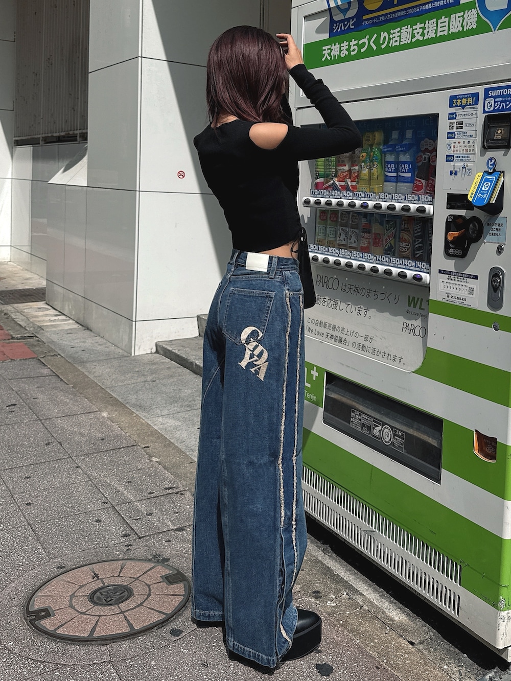 ブルー系のデニムパンツ、ブラック系のニット/セーター、ブラック系のハンドバッグを着用したレディースの秋コーディネートの2枚目の写真