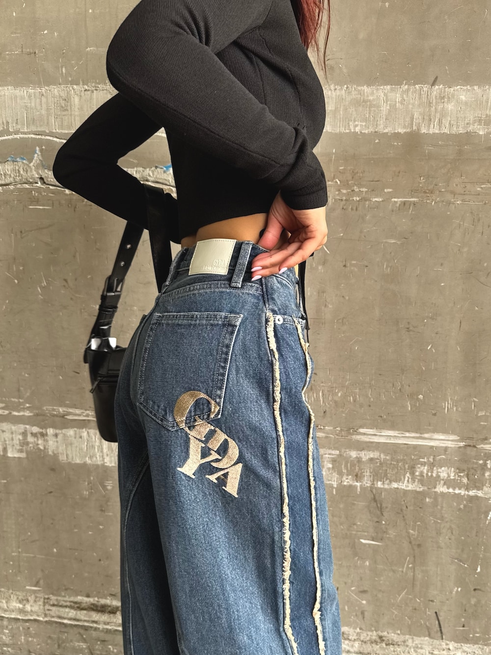 ブルー系のデニムパンツ、ブラック系のニット/セーター、ブラック系のハンドバッグを着用したレディースの秋コーディネートの3枚目の写真