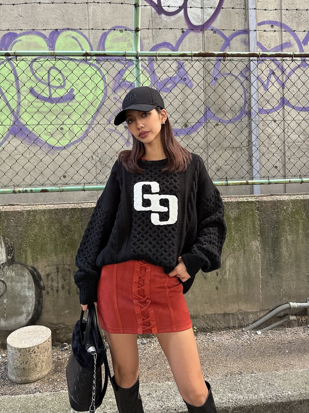 ブラック系のニット/セーター、オレンジ系のワンピース、ブラック系のショルダーバッグを着用したレディースの秋コーディネートの3枚目の写真