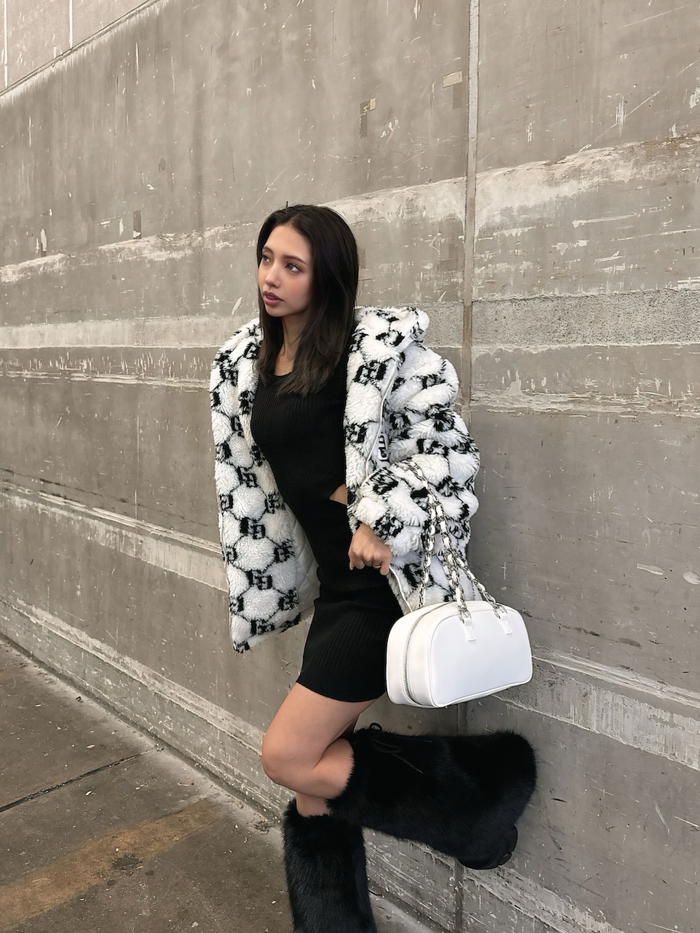 ホワイト系のブルゾン、ブラック系のワンピース、ブラック系のブーツを着用したレディースの秋コーディネートの3枚目の写真