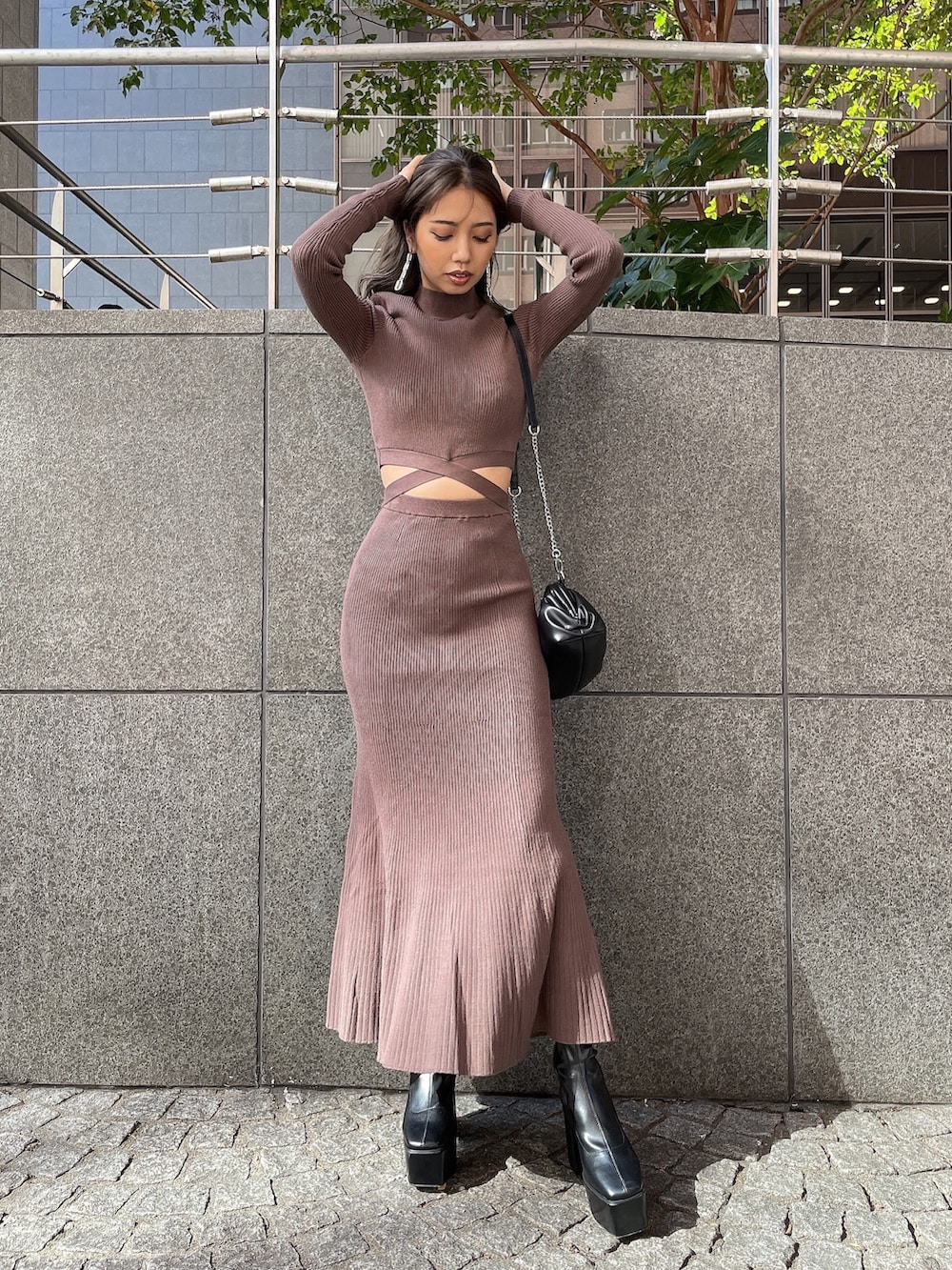 ブラック系のクラッチバッグ、ブラック系のブーツ、ブラウン系のワンピースを着用したレディースの秋コーディネートの6枚目の写真