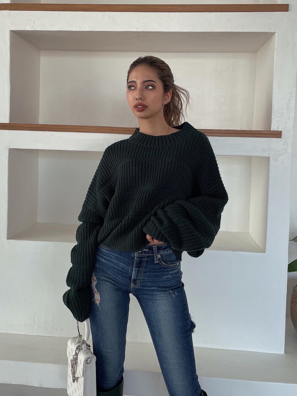 グリーン系のニット/セーター、グリーン系のブーツ、ブルー系のデニムパンツを着用したレディースの冬コーディネートの6枚目の写真