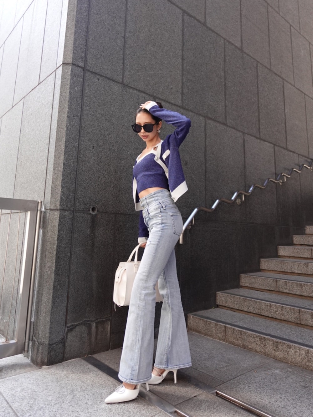 ブルー系のニット/セーター、ブルー系のデニムパンツ、ホワイト系のパンプスを着用したレディースの春コーディネートの4枚目の写真