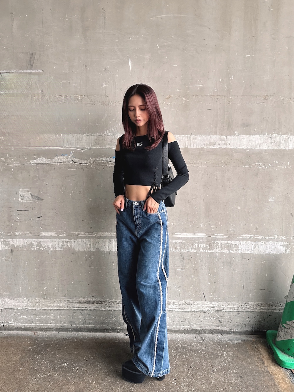 ブルー系のデニムパンツ、ブラック系のニット/セーター、ブラック系のハンドバッグを着用したレディースの秋コーディネートの4枚目の写真