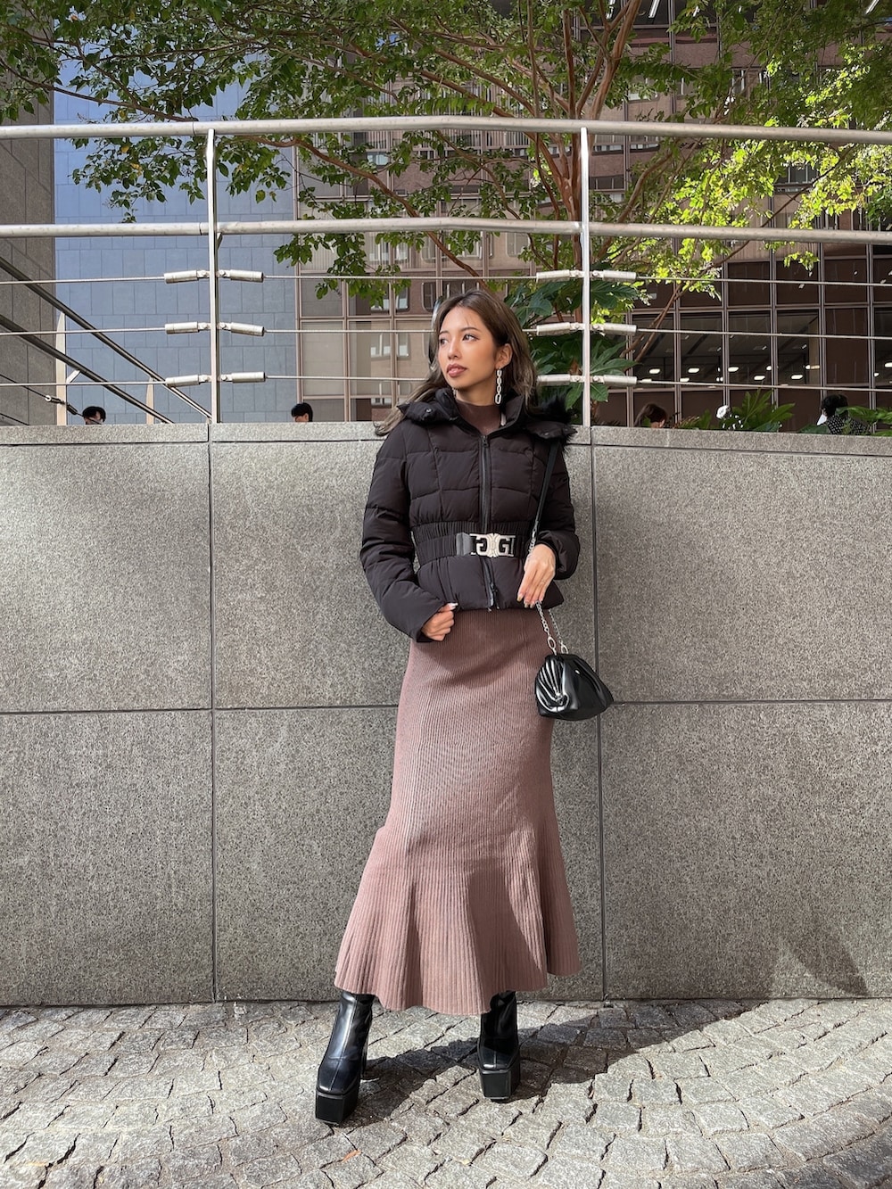 ブラック系のクラッチバッグ、ブラック系のブーツ、ブラウン系のワンピースを着用したレディースの秋コーディネートの2枚目の写真