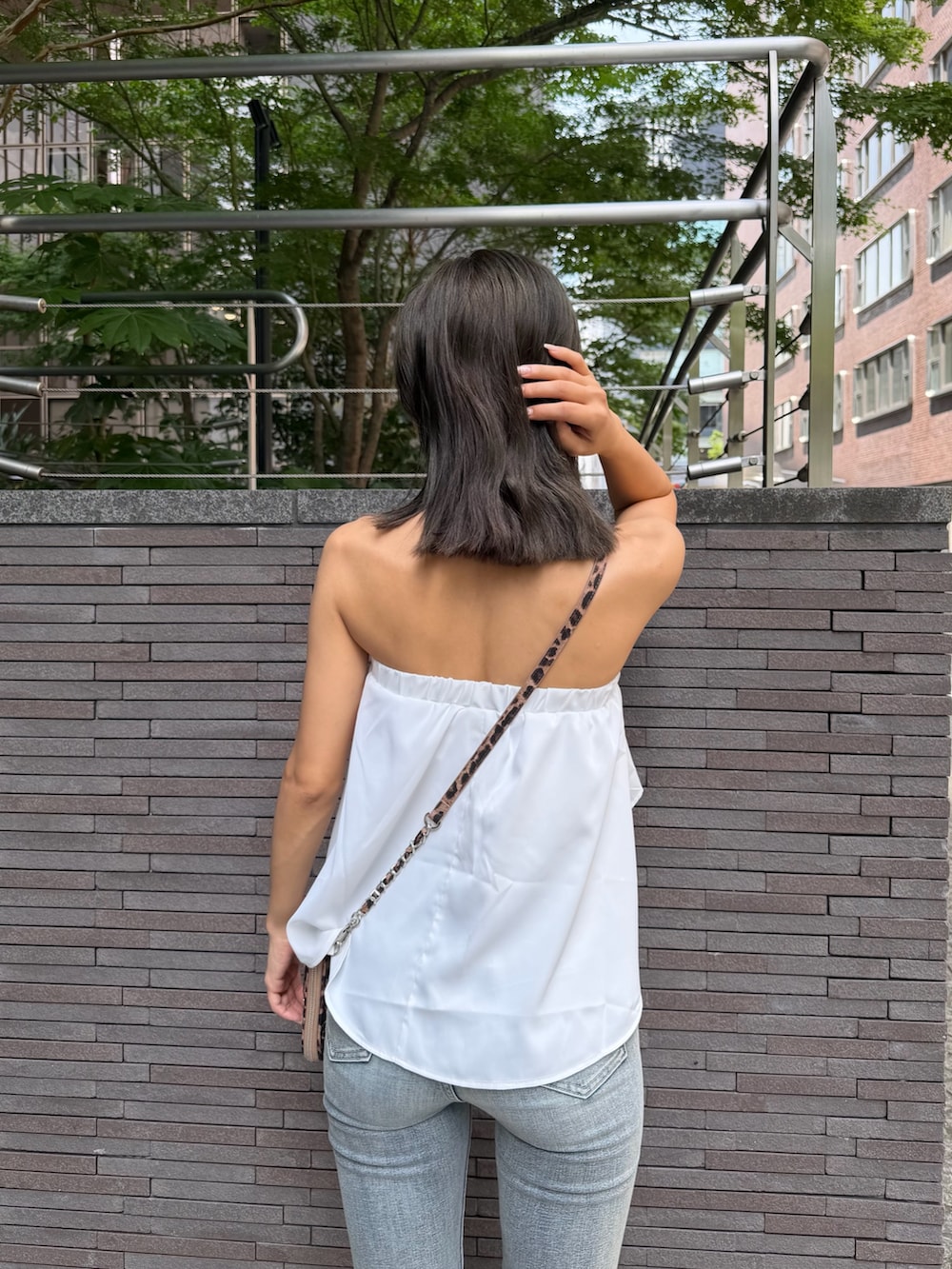 ホワイト系のチューブトップ、その他のショルダーバッグ、ブルー系のデニムパンツを着用したレディースの夏コーディネートの4枚目の写真