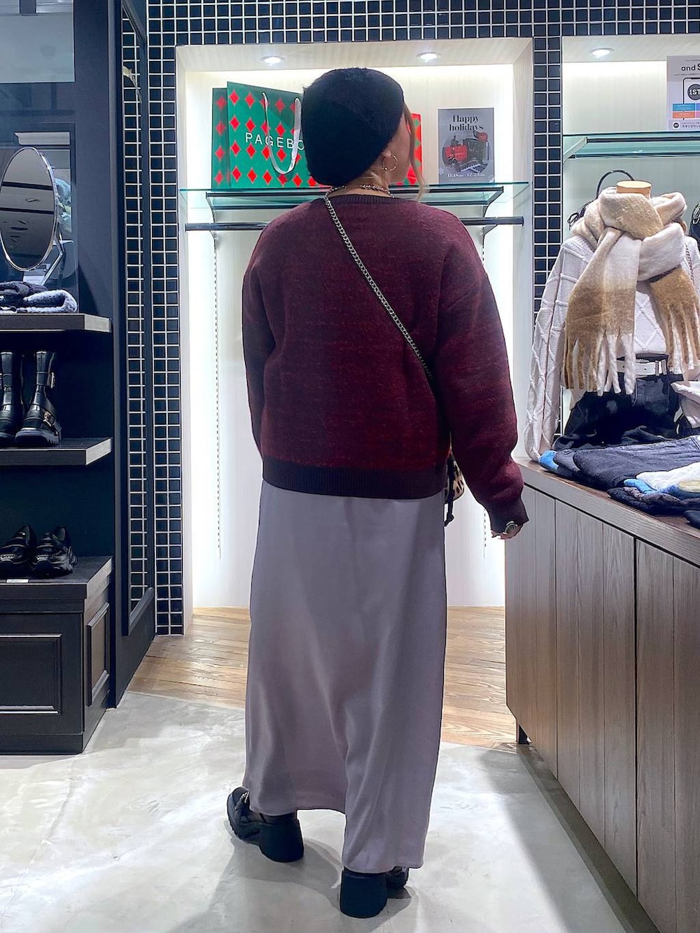 ブラック系のブーツ、その他のハンドバッグ、グレー系のスカートを着用したレディースの冬コーディネートの3枚目の写真