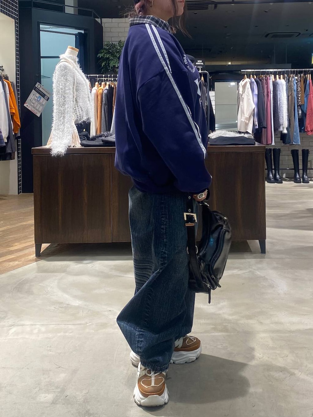 ベージュ系のスニーカー、ブラック系のショルダーバッグ、ブルー系のデニムパンツを着用したレディースの秋コーディネートの5枚目の写真