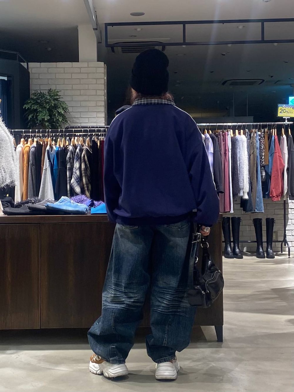 ベージュ系のスニーカー、ブラック系のショルダーバッグ、ブルー系のデニムパンツを着用したレディースの秋コーディネートの3枚目の写真