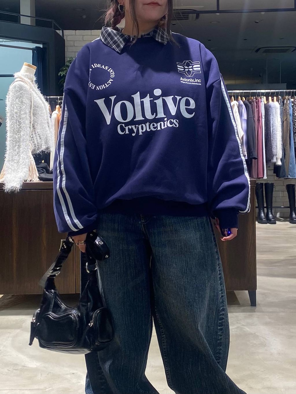 ベージュ系のスニーカー、ブラック系のショルダーバッグ、ブルー系のデニムパンツを着用したレディースの秋コーディネートの4枚目の写真