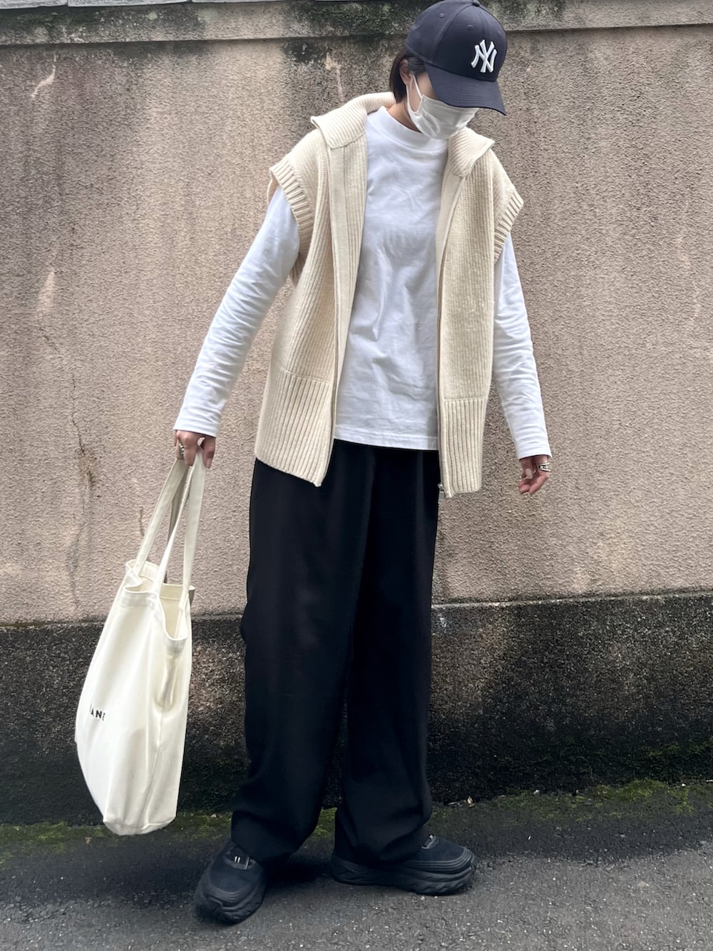 ブラック系のスニーカー、ブラック系のスラックス、ホワイト系のベストを着用したレディースの秋コーディネートの2枚目の写真