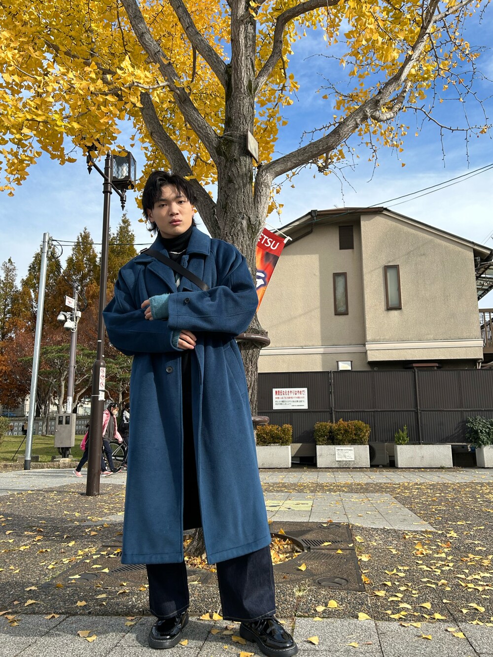 ブルー系のステンカラーコート、ブラック系のニット/セーター、ブルー系のデニムパンツを着用したメンズの冬コーディネートの2枚目の写真