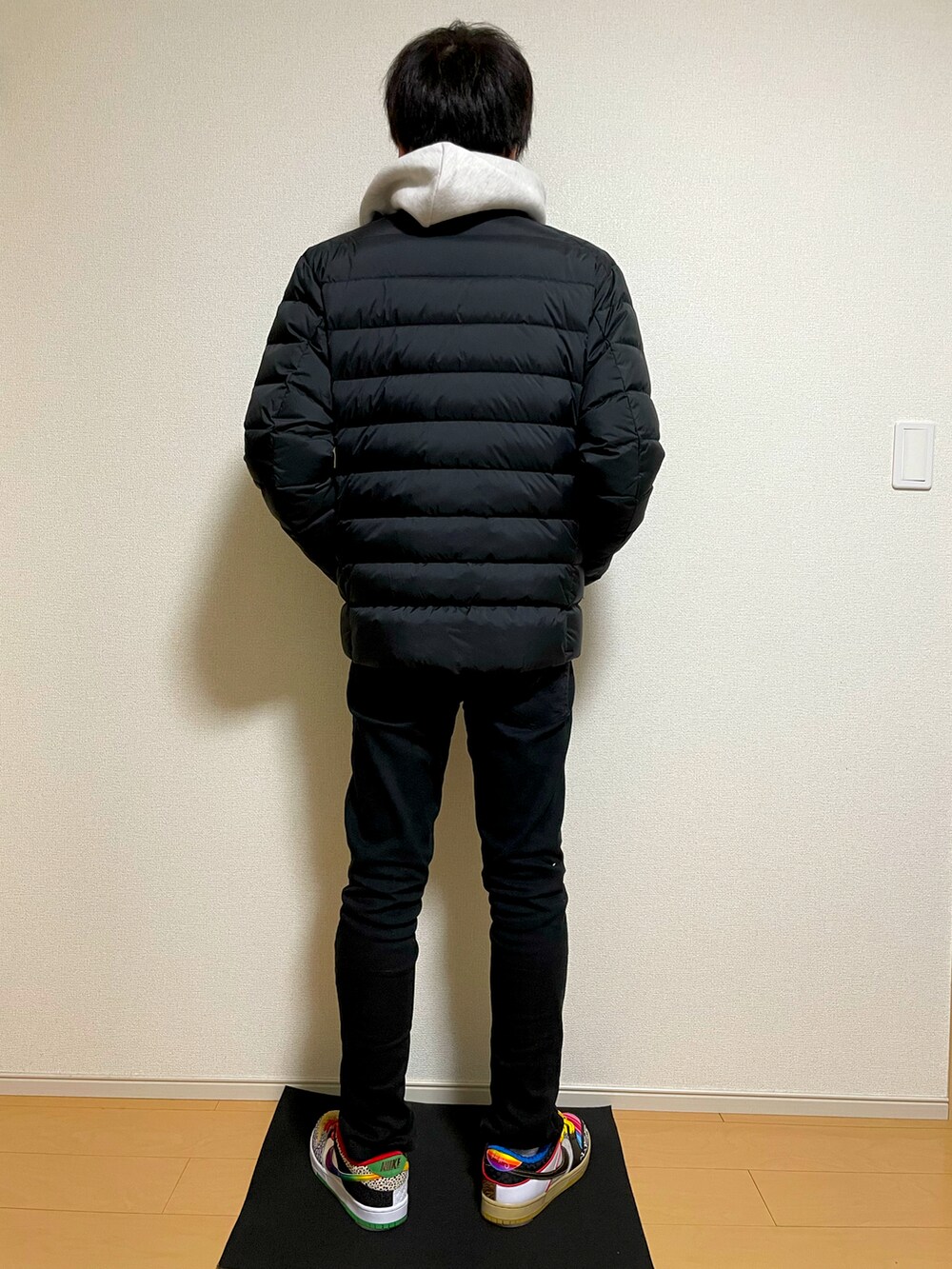 グレー系のパーカー、ブラック系のダウンジャケット/コート、ブラック系のパンツを着用したメンズの冬コーディネートの3枚目の写真