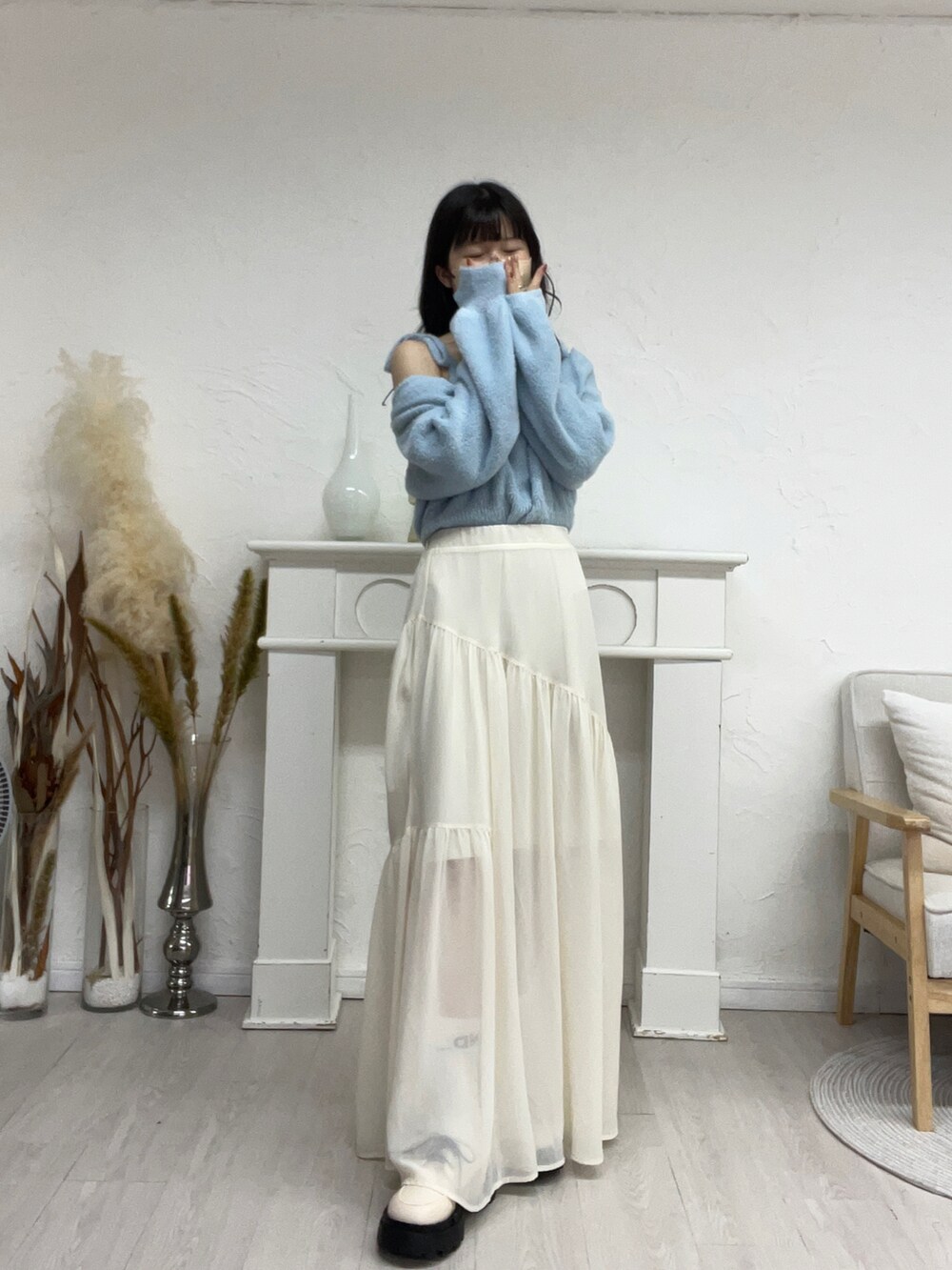 ブラウン系のカーディガン/ボレロ、ホワイト系のスカート、ホワイト系のパンプスを着用したレディースの秋コーディネートの2枚目の写真