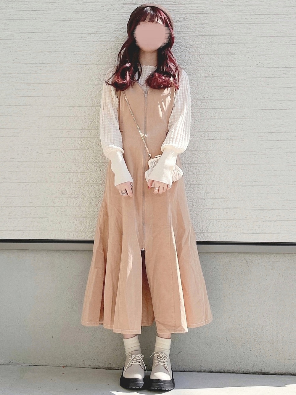 ベージュ系のテーラードジャケット、ホワイト系のニット/セーター、ベージュ系のジャンパースカートを着用したレディースの冬コーディネートの2枚目の写真