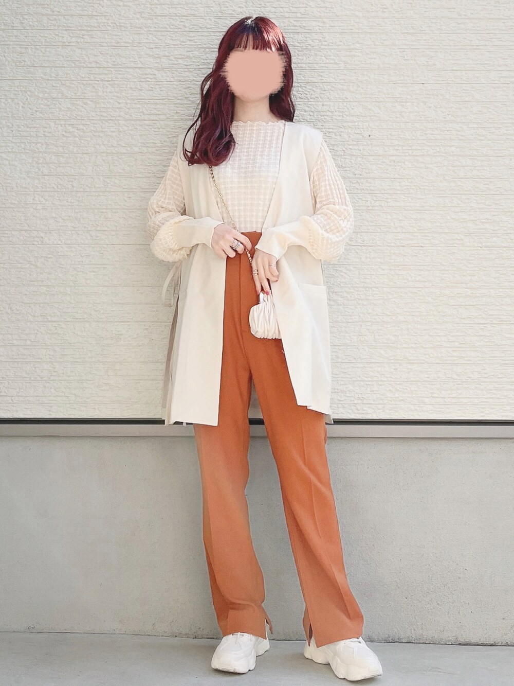 ホワイト系のベスト、ホワイト系のニット/セーター、オレンジ系のスラックスを着用したレディースの春コーディネートの2枚目の写真