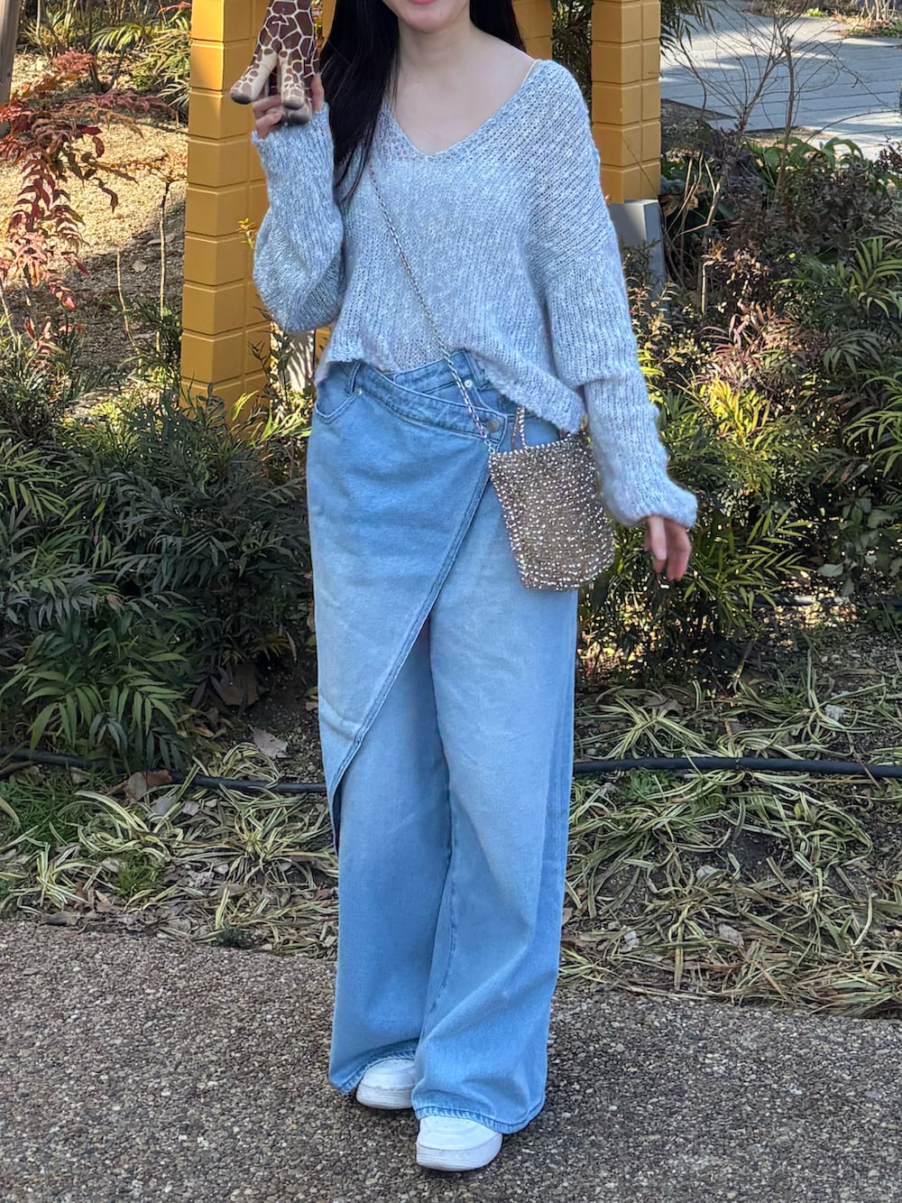 ブルー系のワンピース、ブルー系のデニムパンツ、ホワイト系のスニーカーを着用したレディースの春コーディネートの2枚目の写真