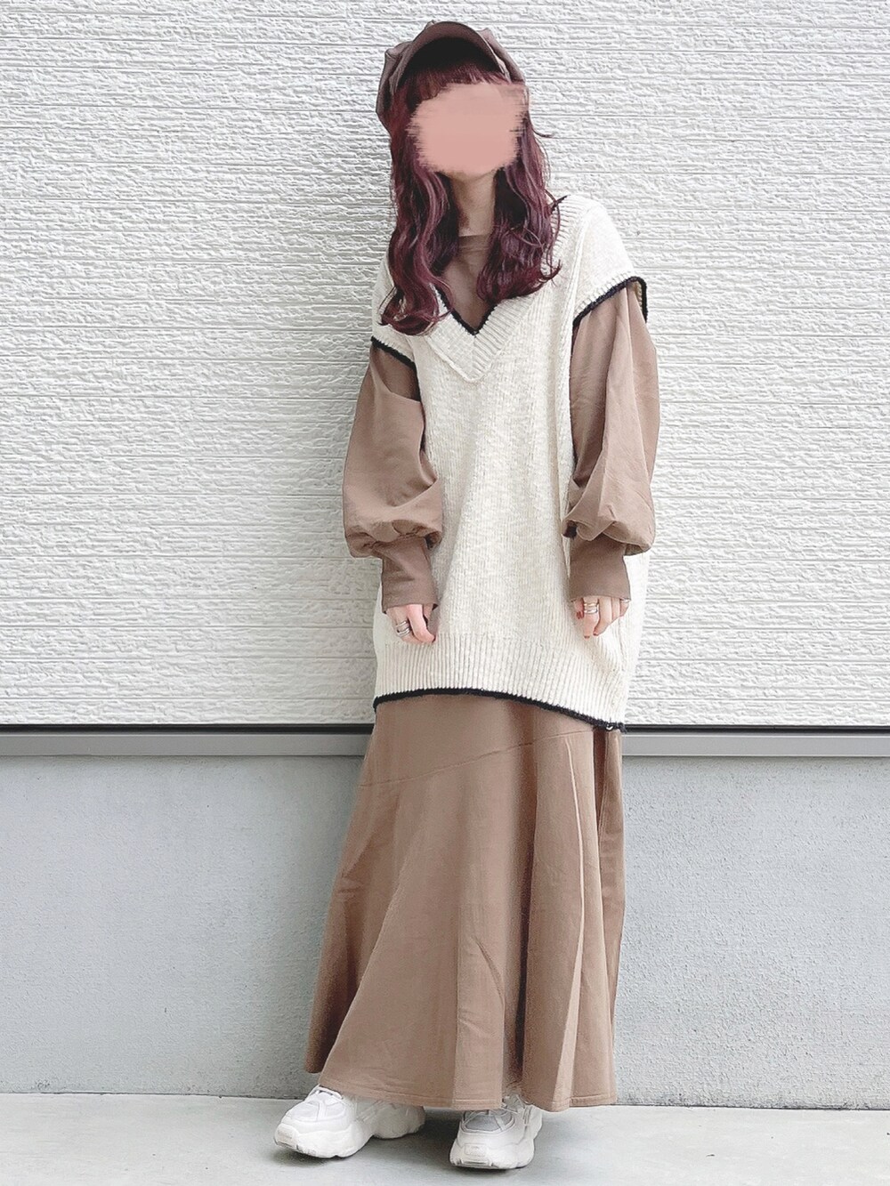 ホワイト系のベスト、ブラウン系のワンピース、ベージュ系のスニーカーを着用したレディースの冬コーディネートの2枚目の写真