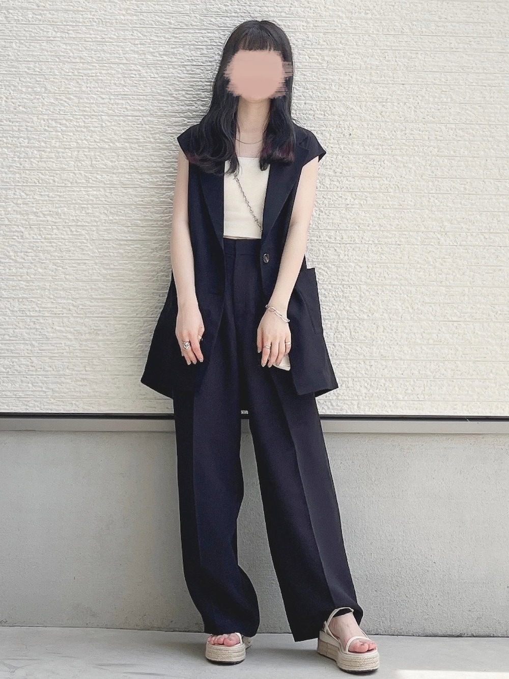 ブラック系のベスト、ホワイト系のキャミソール、ブラック系のスラックスを着用したレディースの夏コーディネートの2枚目の写真