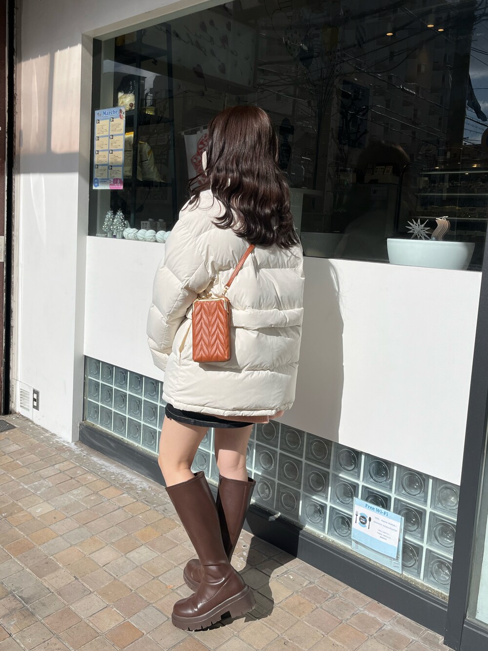 ホワイト系のダウンジャケット/コート、ブラウン系のブーツを着用したレディースの春コーディネートの2枚目の写真