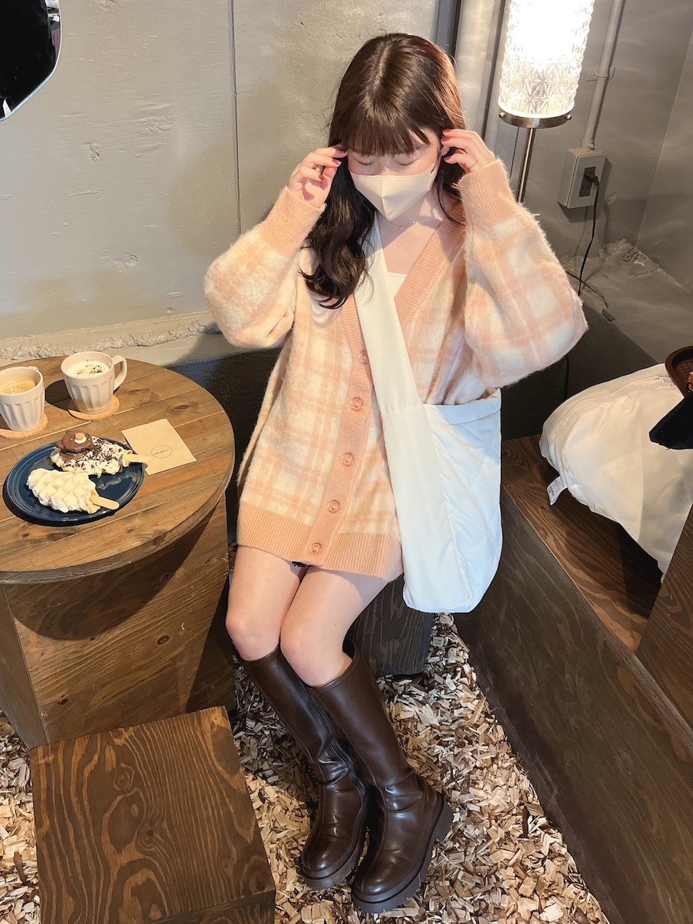 ピンク系のカーディガン/ボレロ、ホワイト系のショルダーバッグ、ブラウン系のブーツを着用したレディースの春コーディネートの2枚目の写真