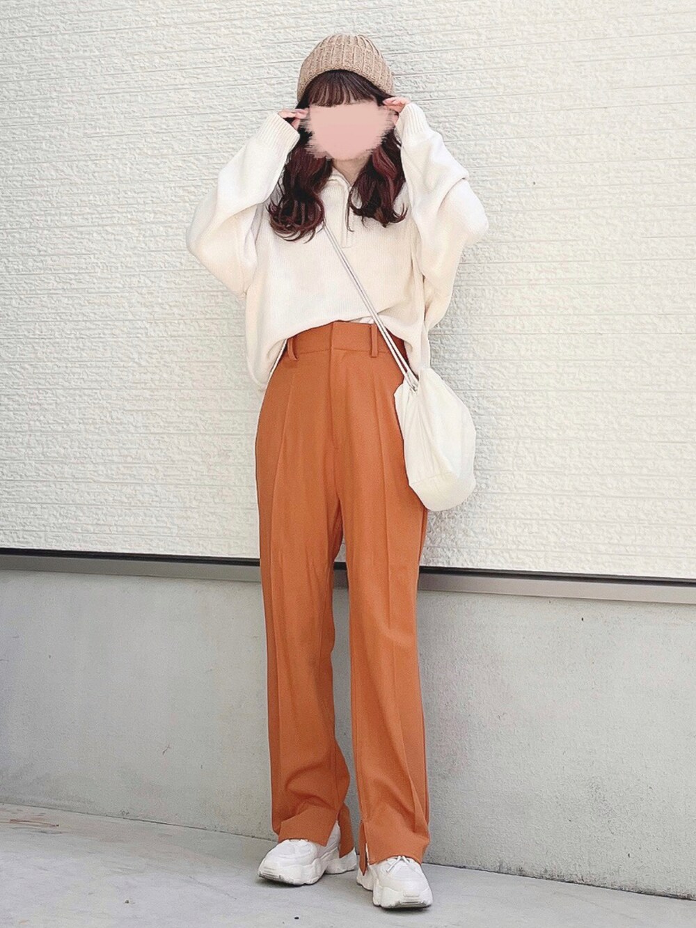 ホワイト系のニット/セーター、オレンジ系のスラックス、ホワイト系のショルダーバッグを着用したレディースの夏コーディネートの2枚目の写真
