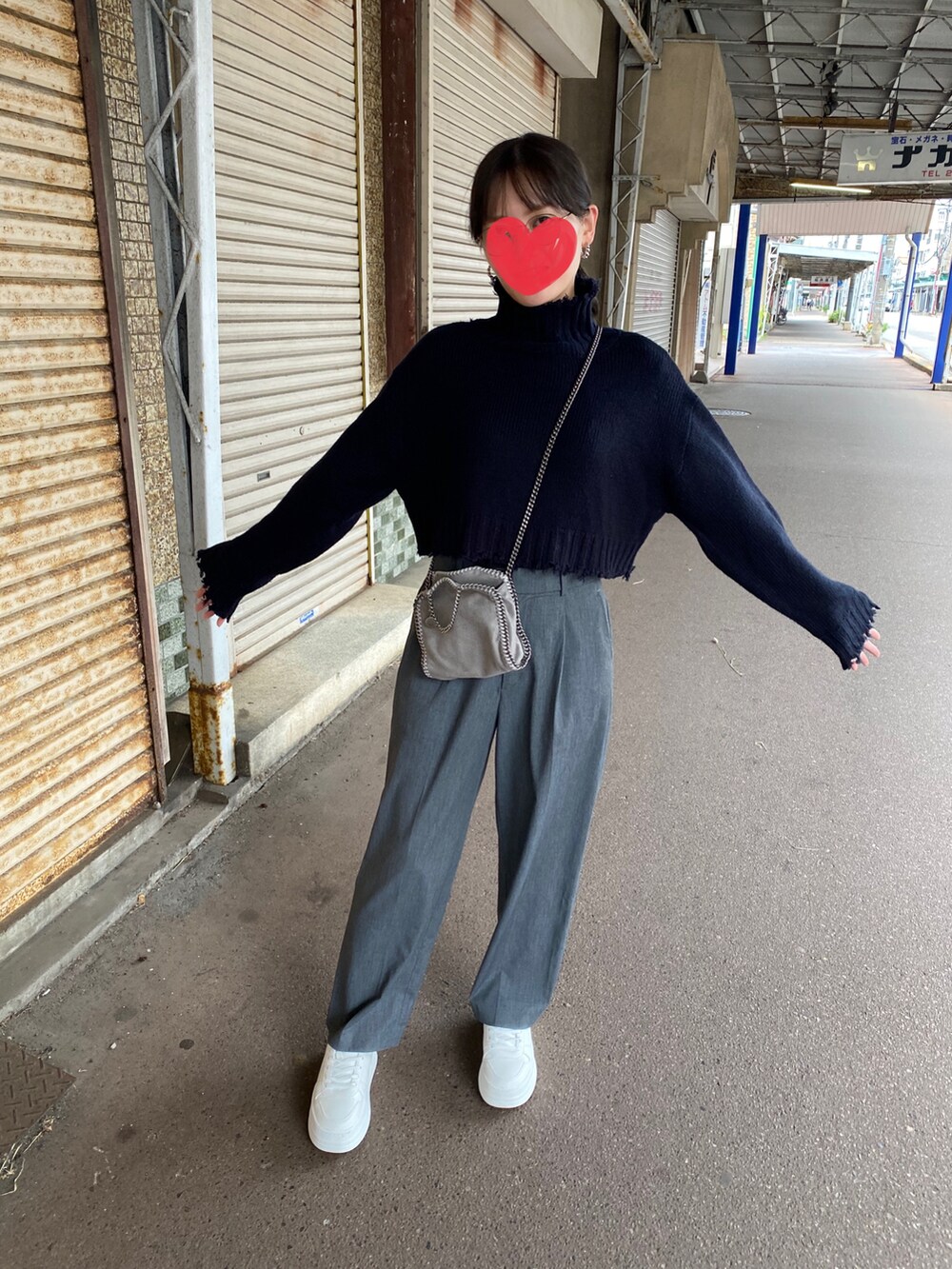 グレー系のパンツ、ブラック系のニット/セーター、ホワイト系のスニーカーを着用したレディースの秋コーディネートの2枚目の写真