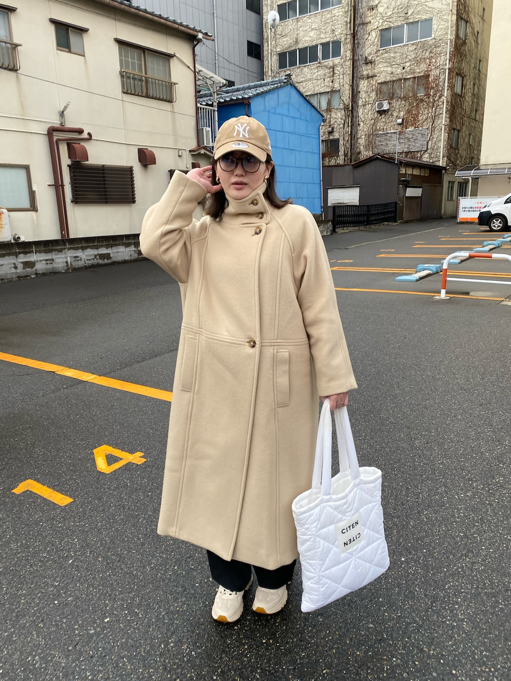 ホワイト系のトートバッグ、ベージュ系のチェスターコートを着用したレディースの冬コーディネートの3枚目の写真