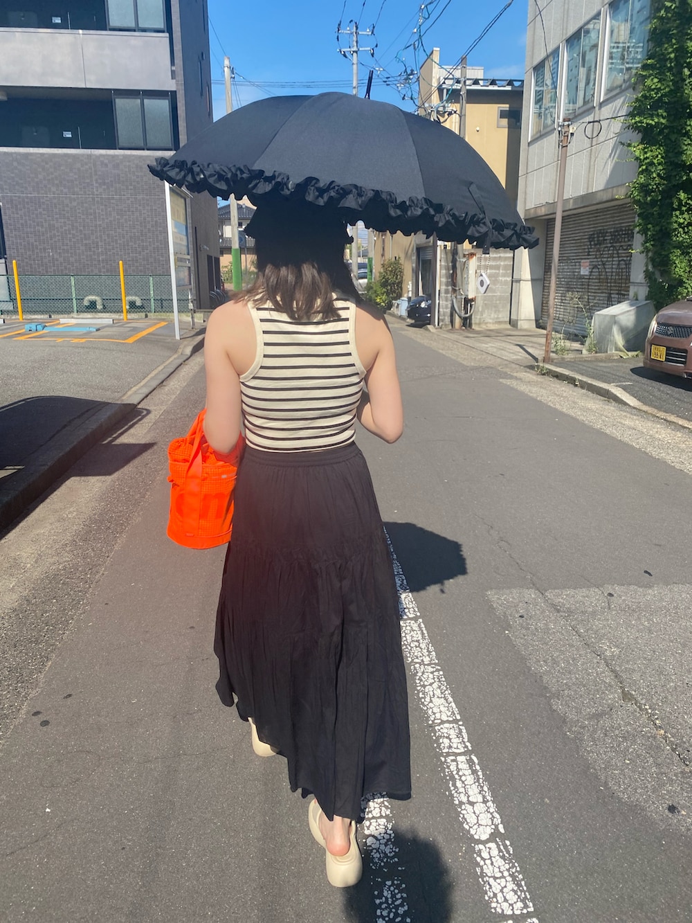 ホワイト系のタンクトップ、オレンジ系のショルダーバッグ、ブラック系のスカートを着用したレディースの夏コーディネートの3枚目の写真