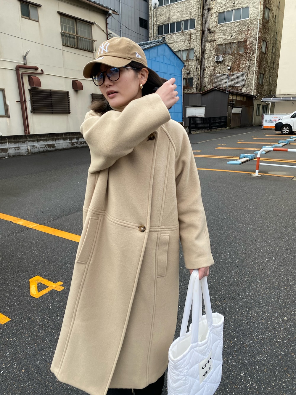 ホワイト系のトートバッグ、ベージュ系のチェスターコートを着用したレディースの冬コーディネートの4枚目の写真