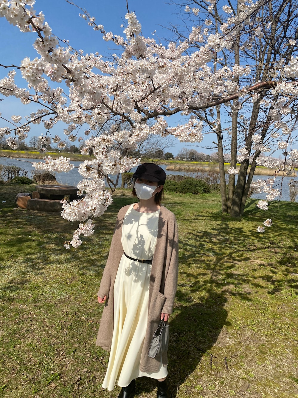 ベージュ系のカーディガン/ボレロ、グレー系のハンドバッグ、ホワイト系のワンピースを着用したレディースの春コーディネートの2枚目の写真