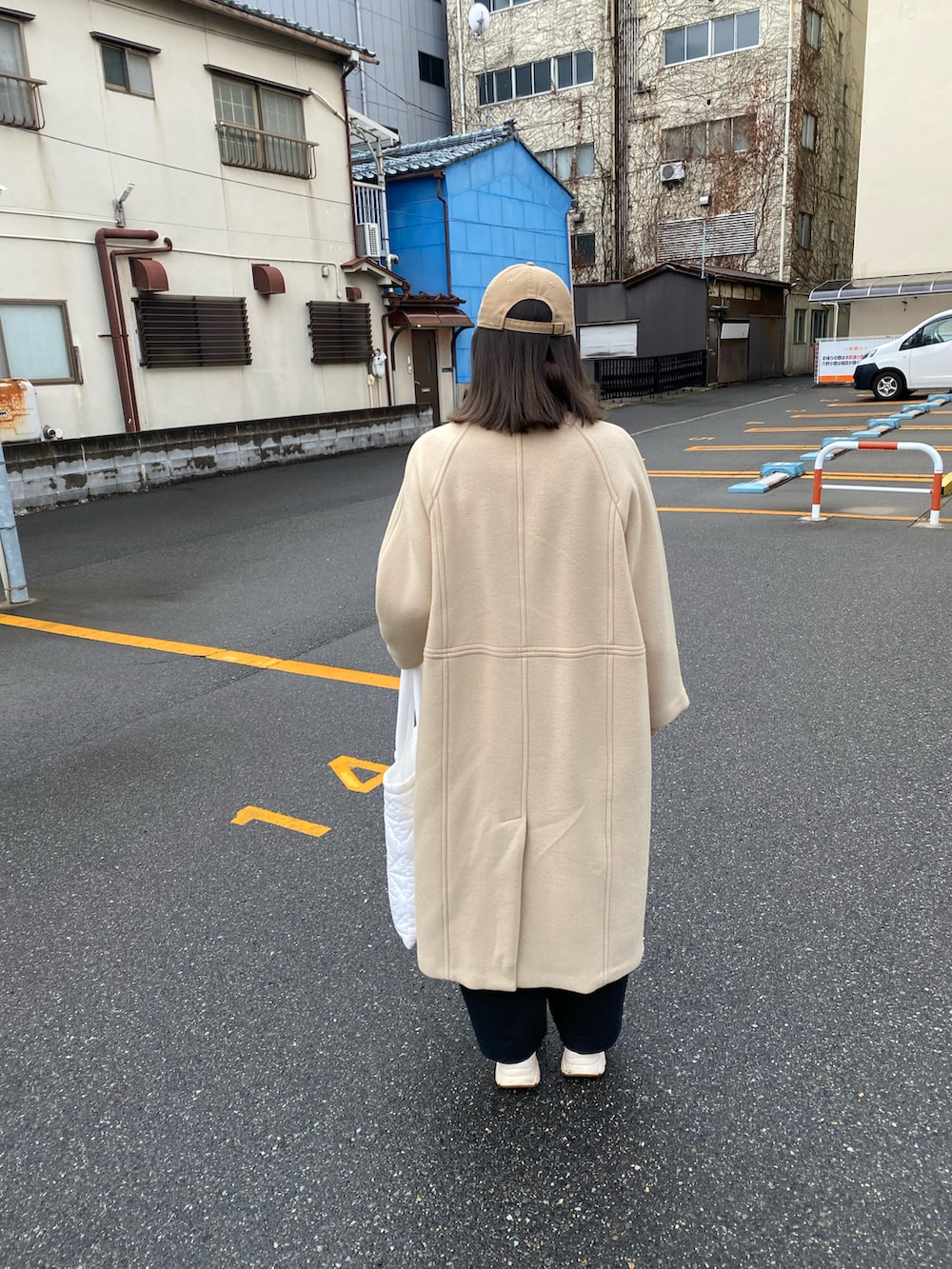 ホワイト系のトートバッグ、ベージュ系のチェスターコートを着用したレディースの冬コーディネートの5枚目の写真