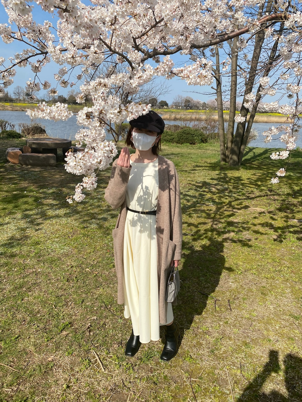 ベージュ系のカーディガン/ボレロ、グレー系のハンドバッグ、ホワイト系のワンピースを着用したレディースの春コーディネートの3枚目の写真