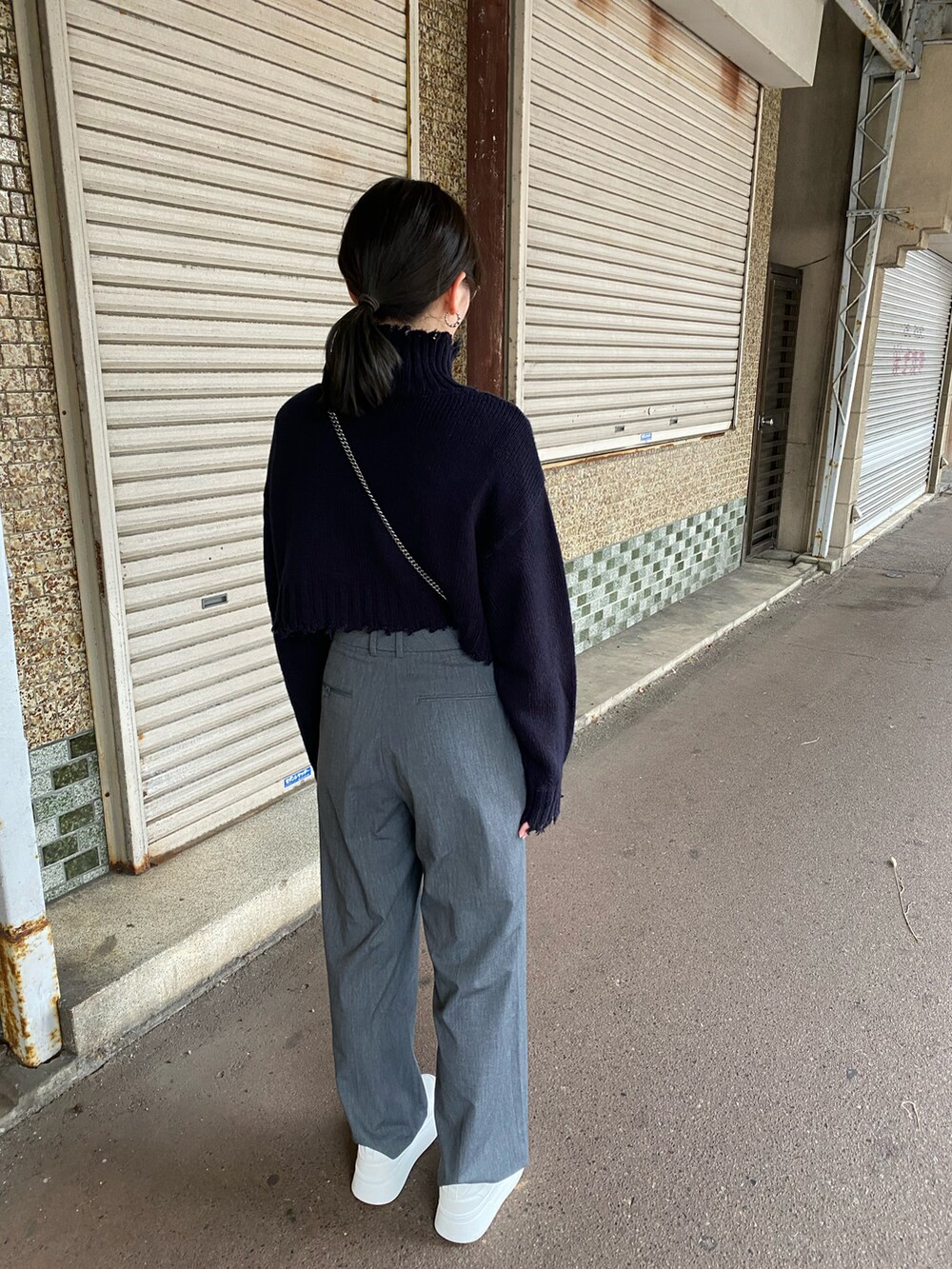 グレー系のパンツ、ブラック系のニット/セーター、ホワイト系のスニーカーを着用したレディースの秋コーディネートの4枚目の写真