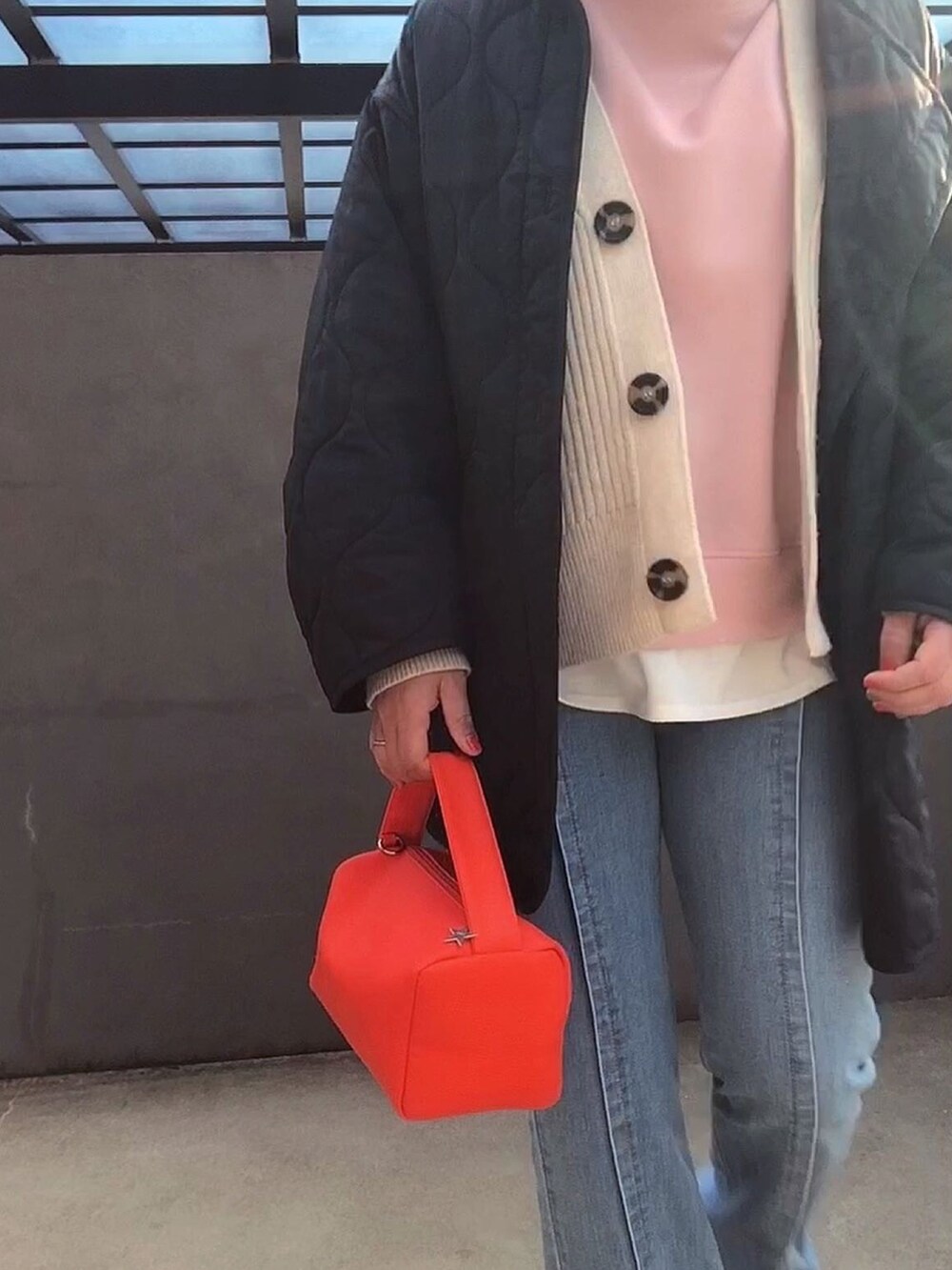 ブラック系のナイロンジャケット、オレンジ系のショルダーバッグを着用したレディースの春コーディネートの2枚目の写真