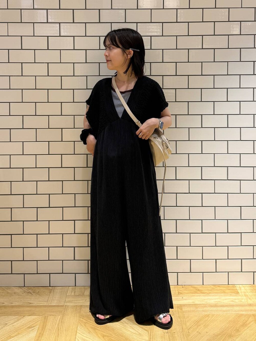 シルバー系のサンダル、ブラック系のサロペット/オーバーオール、ホワイト系のショルダーバッグを着用したレディースの夏コーディネートの2枚目の写真