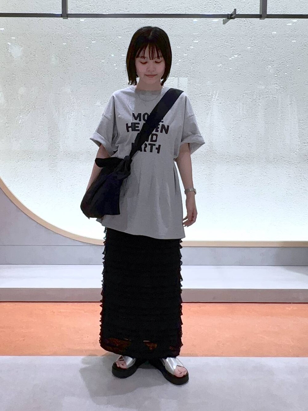 ブラック系のスカート、ブラック系のショルダーバッグ、シルバー系のサンダルを着用したレディースの夏コーディネートの2枚目の写真