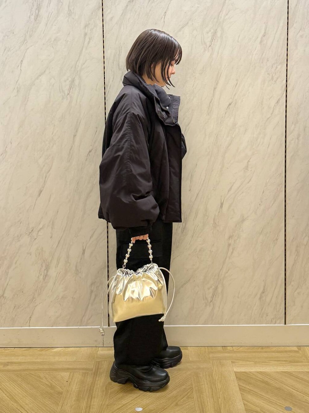 ブラック系のその他アウター、ブラック系のブーツ、シルバー系のショルダーバッグを着用したレディースの冬コーディネートの3枚目の写真