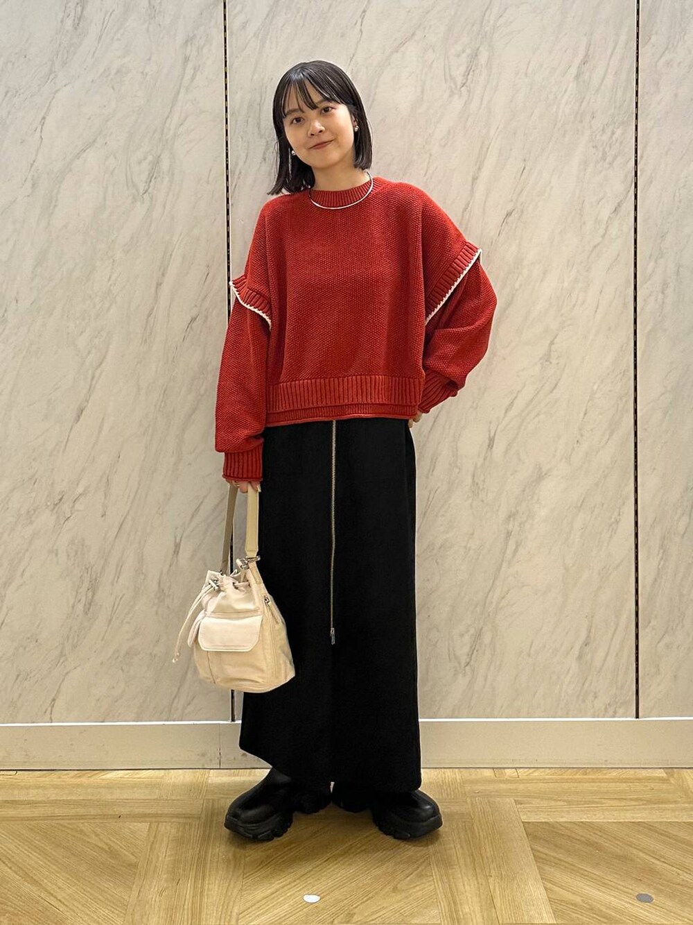 レッド系のニット/セーター、ホワイト系のショルダーバッグ、ブラック系のブーツを着用したレディースの秋コーディネートの2枚目の写真
