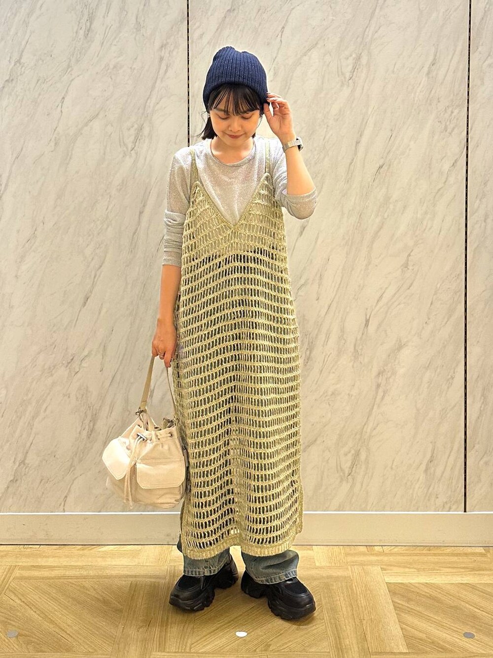 シルバー系のTシャツ/カットソー、ブラック系のスニーカー、ブルー系のデニムパンツを着用したレディースの秋コーディネートの2枚目の写真