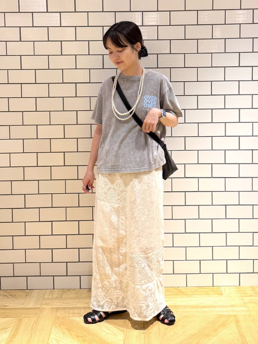 ブラック系のショルダーバッグ、ホワイト系のスカート、ブラック系のサンダルを着用したレディースの夏コーディネートの2枚目の写真